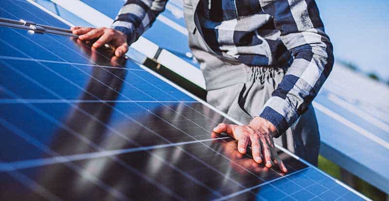 Man worker in the firld by the solar panels